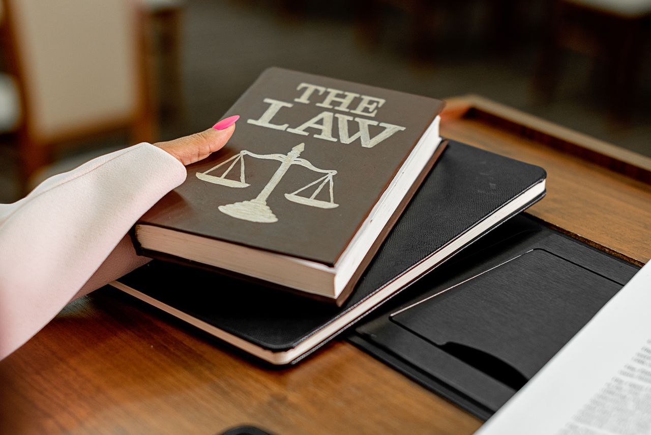 The Art of Drawing Readers In: Your attractive post title goes here Closeup image of a law book titled The Law on a wooden desk with scales of justice.