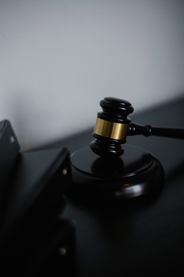 Services Black wooden gavel with golden strip on table near stack of folders in courthouse