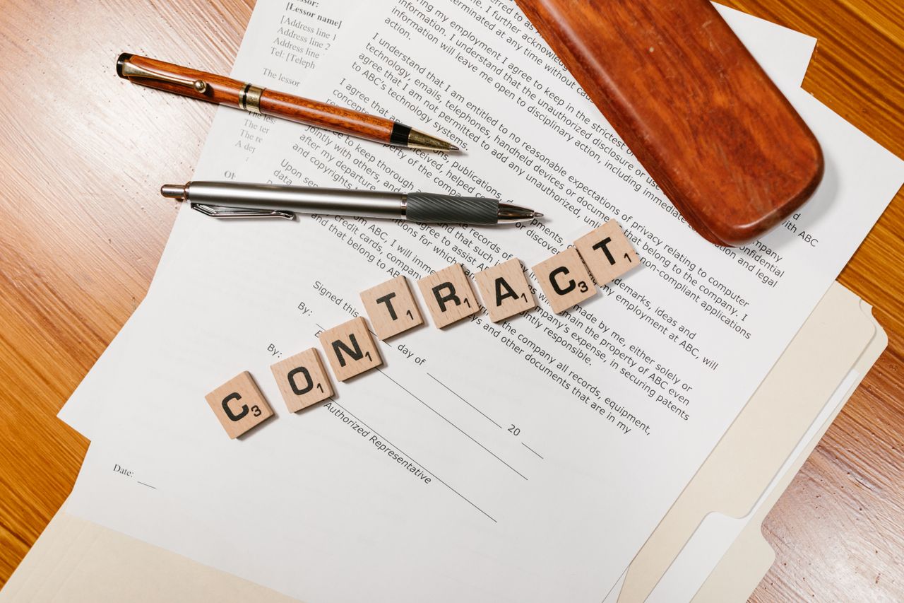 Close-up of contract papers with Scrabble tiles spelling CONTRACT.