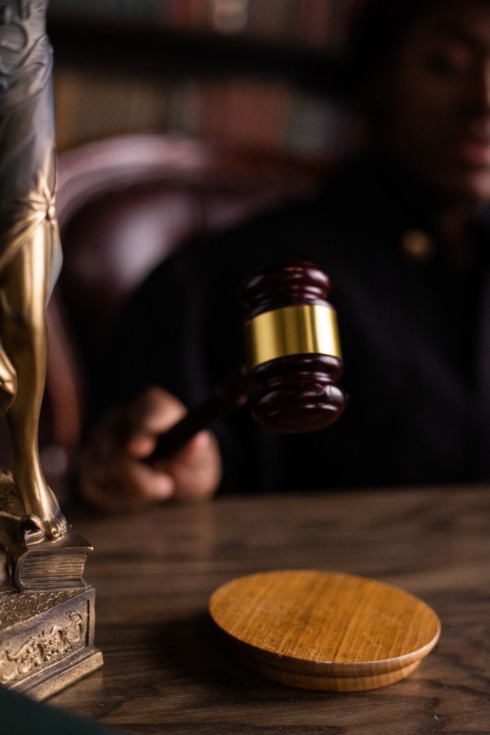 Services Close-up of a judge holding a gavel, symbolizing justice and law in a courtroom setting.